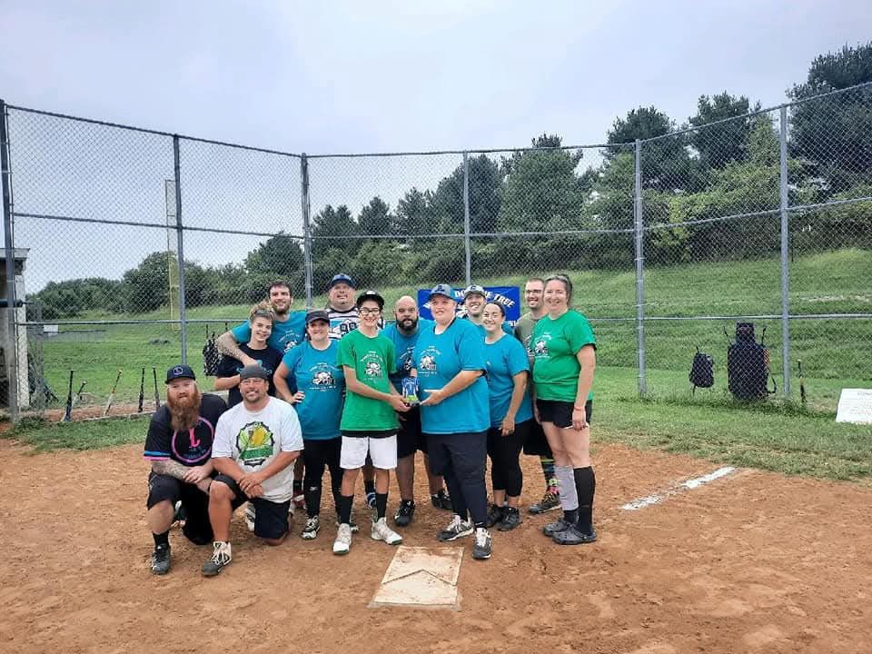 A team in teal shirts with their trophy at home plate